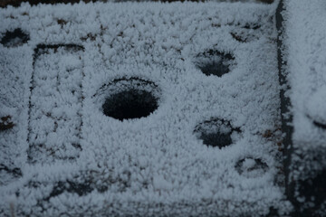 A detailed closeup view of a snowy surface featuring various holes scattered throughout it,...