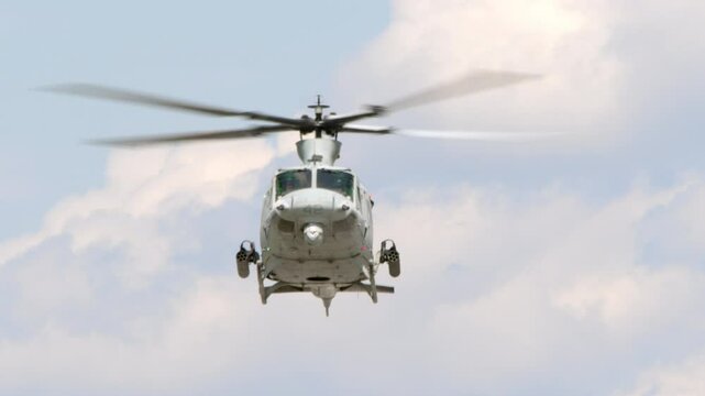 A United States Marine Corp Bell UH-1 Huey attack helicopter armed with rocket launchers hovers in front of the camera in this slow motion shot.