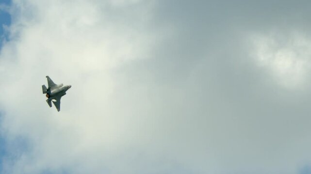 An F-35 warplane banks hard in the sky.