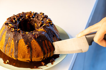 Slicing a delicious chocolate cake with a knife. Close-up of hands cutting a rich dessert.
