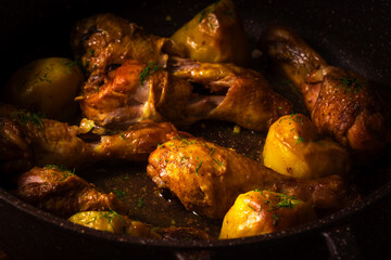 Baked chicken with potatoes in frying pan.