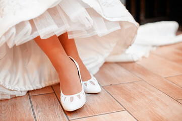 Close-Up of Bride's Feet in Wedding Shoes Under Elegant Gown