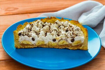 Authentic banoffee cake with banana and caramel sauce filling sprinkled with grated dark chocolate and coffee . English traditional pie