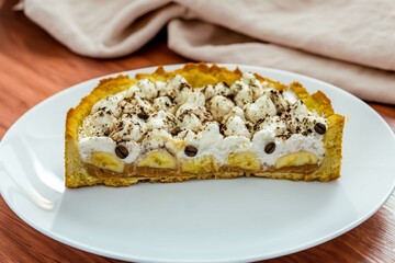 Authentic banoffee cake with banana and caramel sauce filling sprinkled with grated dark chocolate and coffee . English traditional pie