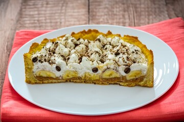 Authentic banoffee cake with banana and caramel sauce filling sprinkled with grated dark chocolate and coffee . English traditional pie