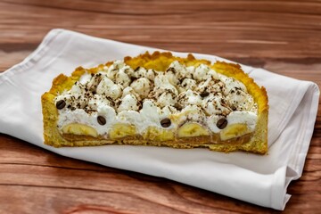 Authentic banoffee cake with banana and caramel sauce filling sprinkled with grated dark chocolate and coffee . English traditional pie