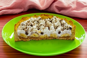 Authentic banoffee cake with banana and caramel sauce filling sprinkled with grated dark chocolate and coffee . English traditional pie