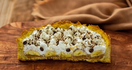 Authentic banoffee cake with banana and caramel sauce filling sprinkled with grated dark chocolate and coffee . English traditional pie
