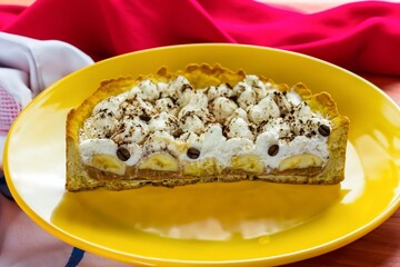 Authentic banoffee cake with banana and caramel sauce filling sprinkled with grated dark chocolate and coffee . English traditional pie