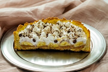 Authentic banoffee cake with banana and caramel sauce filling sprinkled with grated dark chocolate and coffee . English traditional pie
