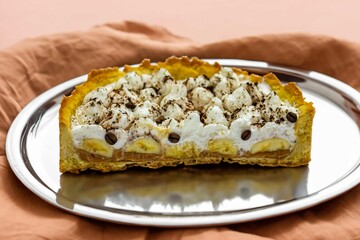 Authentic banoffee cake with banana and caramel sauce filling sprinkled with grated dark chocolate and coffee . English traditional pie