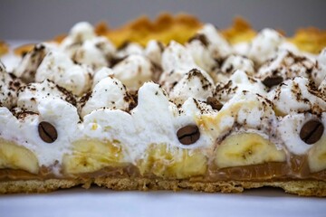 Authentic banoffee cake with banana and caramel sauce filling sprinkled with grated dark chocolate and coffee . English traditional pie