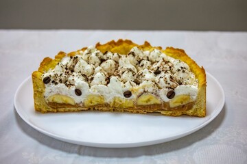 Authentic banoffee cake with banana and caramel sauce filling sprinkled with grated dark chocolate and coffee . English traditional pie