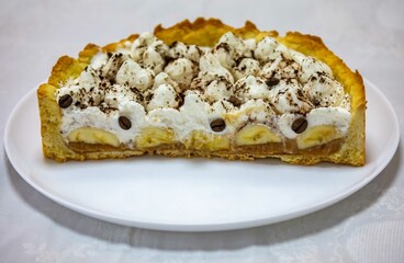 Authentic banoffee cake with banana and caramel sauce filling sprinkled with grated dark chocolate and coffee . English traditional pie