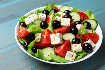 Delicious salad with feta cheese on light blue wooden table, closeup
