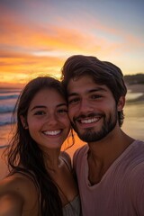 Fototapeta premium A young couple taking a romantic selfie at sunset on the beach, with the colorful sky and ocean waves behind them, both smiling and embracing