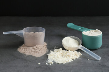 Protein powders in scoops on grey textured table