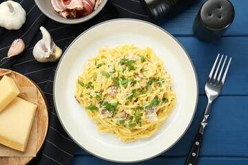 Delicious pasta Carbonara served on blue wooden table, flat lay