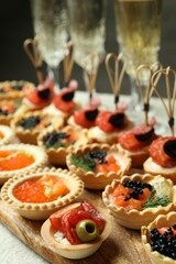 Many different tasty canapes and wine on white table, closeup