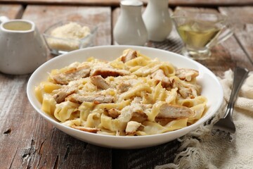 Tasty Alfredo pasta with chicken served on wooden table