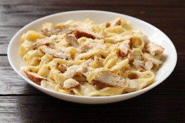 Tasty Alfredo pasta with chicken on wooden table, closeup