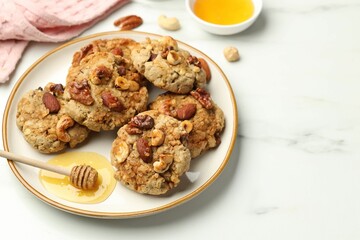 Tasty cookies with nuts and honey dipper on white marble table, closeup. Space for text