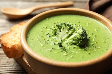 Delicious broccoli cream soup served on wooden table, closeup