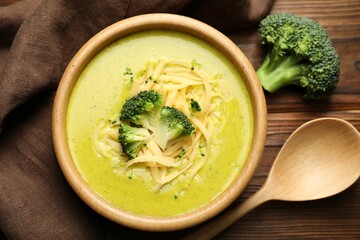 Delicious broccoli cream soup served on wooden table, flat lay