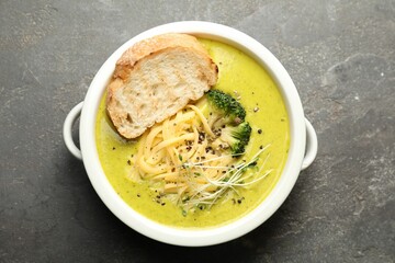 Delicious broccoli cream soup and crouton in bowl on gray textured table, top view