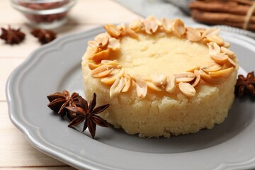 Delicious semolina halva with almond flakes and spices on white wooden table, closeup