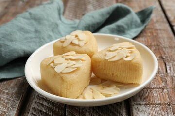 Pieces of delicious sweet semolina halva with almond flakes on wooden table, closeup