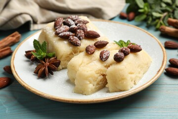 Delicious sweet semolina halva with almonds, spices and mint on light blue wooden table, closeup