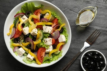 Delicious fresh Greek salad served on black table, flat lay