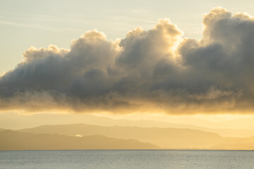 large orange clouds over orange mountains at beach