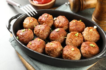 Tasty meatballs in baking dish served on grey table, closeup