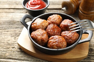 Tasty meatballs in baking dish served on wooden table, closeup