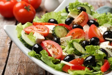 Delicious fresh Greek salad on wooden table, closeup