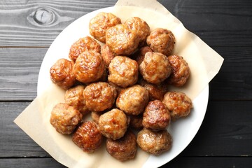 Many delicious meatballs on dark wooden table, top view