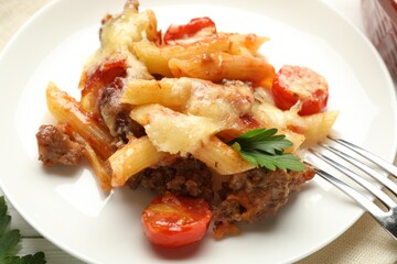 Delicious pasta casserole with cheese, tomatoes, minced meat and parsley on table, closeup