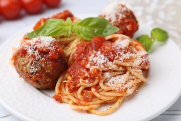 Delicious pasta with meatballs, basil and cheese on light table, closeup