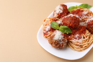 Delicious pasta with meatballs, basil and cheese on beige table, closeup. Space for text