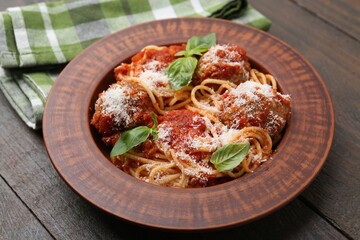 Delicious pasta with meatballs, cheese and basil on wooden table, closeup