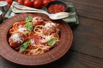 Delicious pasta with meatballs, cheese and basil on wooden table, closeup. Space for text