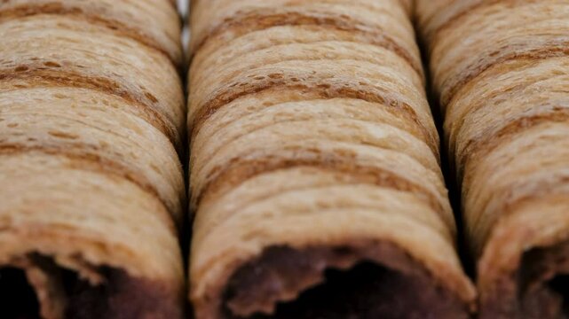 Macro view of cream filled striped wafer rolls. Slider shot. Depth of field, selective focus. Dessert, snack, sweets or confectionery treats concepts. 4k