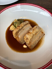 A plate of roast pork belly with sauce.