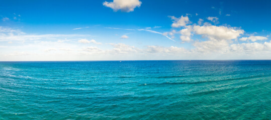 panoramic drone view of ocean with clouds in blue sky