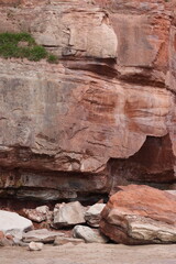 Sandy Red Rock Cliff Face Crumbled onto Beach.