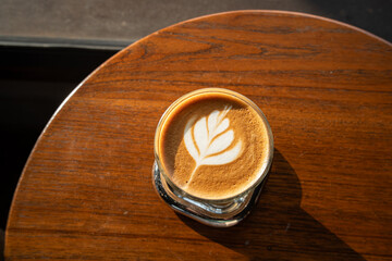Hot coffee latte with latte art milk foam in cup mug on wood desk on top view. As breakfast In a coffee shop at the cafe,during business work concept,vintage style