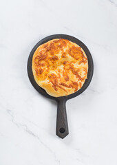 Georgian khachapuri. Flatbread with cheese. On a wooden board. White background. Top view