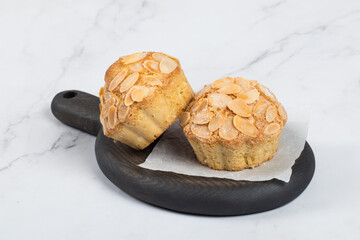 Vegan Small Almond ake with crispy almond petals on top. On a wooden board. White background. Close-up